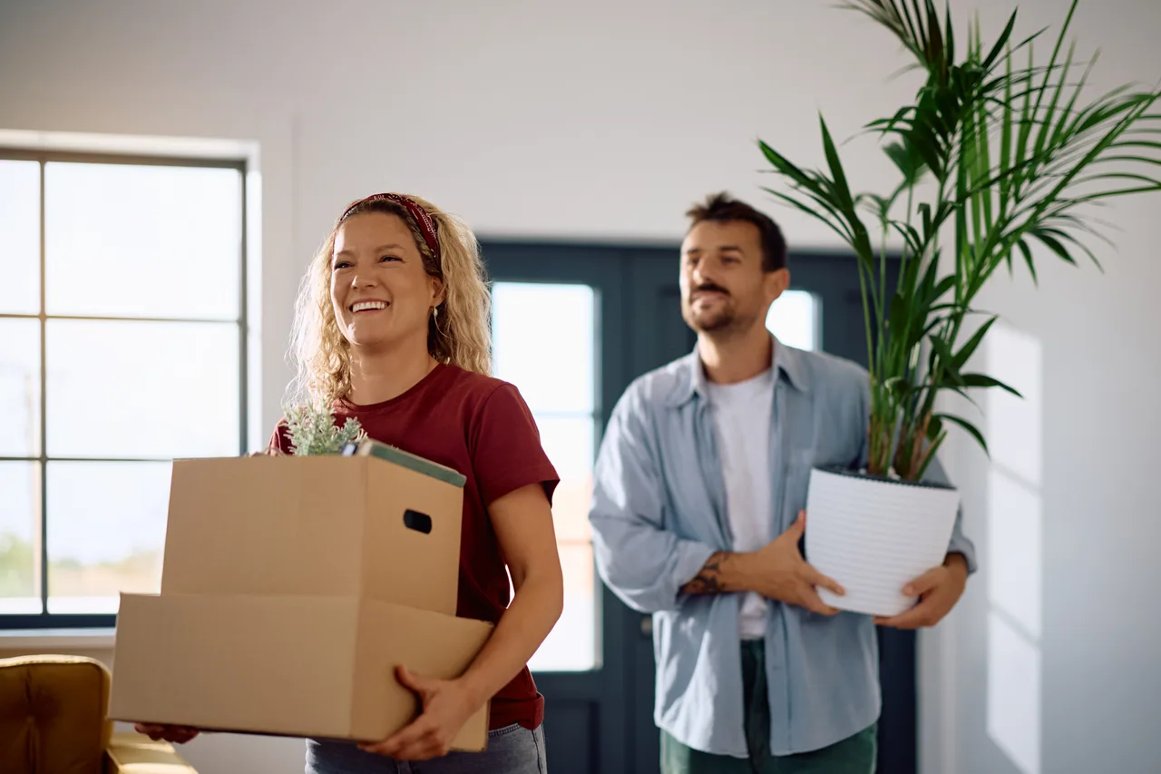 A couple carrying boxes into their new home